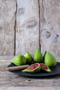 Just harvested green figs on a plate, on an old wooden table, in front of an old wooden wall Just harvested green figs on a plate, on an old wooden table, in front of an old wooden wall
